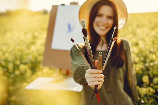 Elegante y hermosa niña pintando en un campo