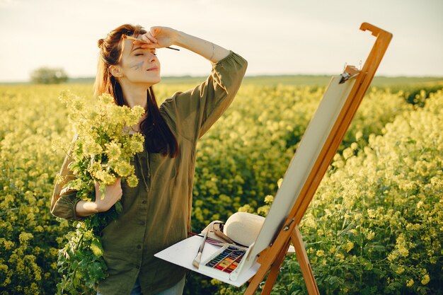 Elegante y hermosa niña pintando en un campo