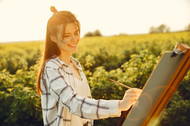 Elegante y hermosa niña pintando en un campo