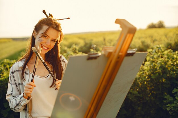 Elegante y hermosa niña pintando en un campo