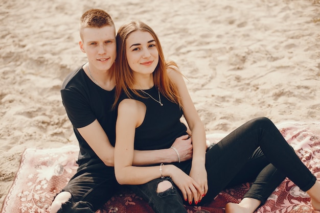 Una elegante y hermosa pareja vestida de negro pasa un buen rato en la playa