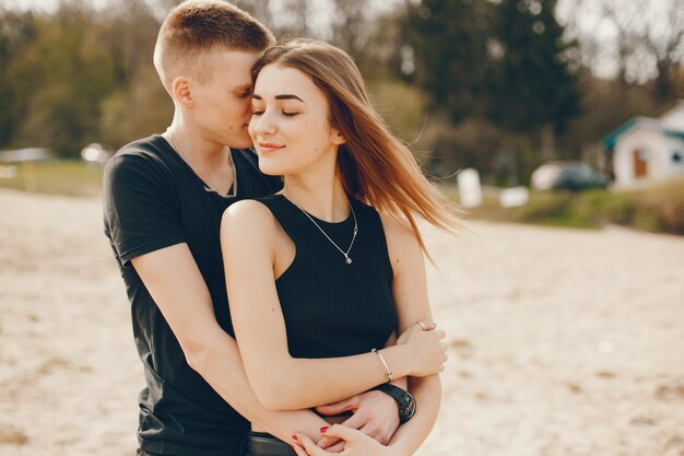 Una elegante y hermosa pareja vestida de negro pasa un buen rato en la playa