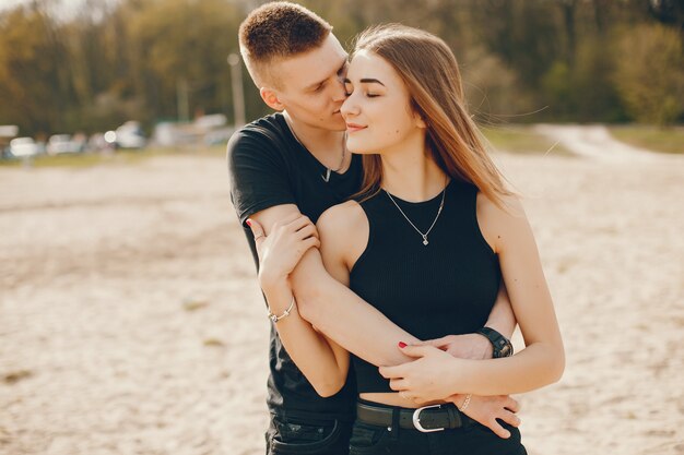 Una elegante y hermosa pareja vestida de negro pasa un buen rato en la playa