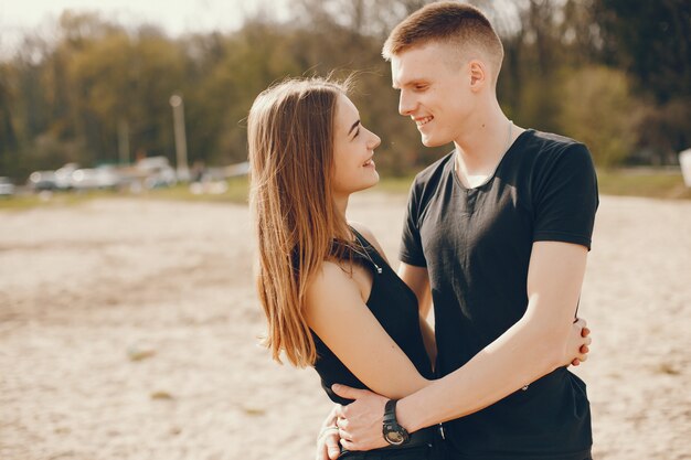 Una elegante y hermosa pareja vestida de negro pasa un buen rato en la playa