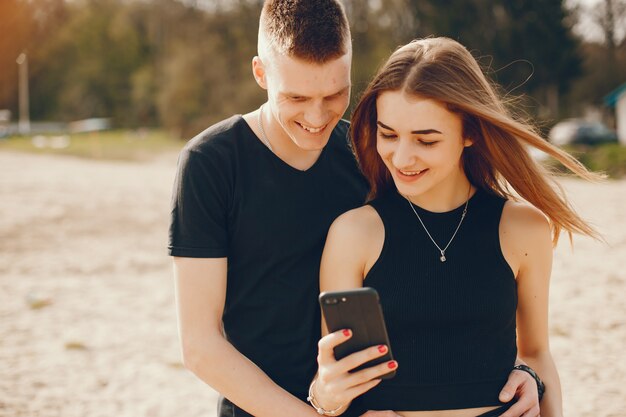 Una elegante y hermosa pareja vestida de negro pasa un buen rato en la playa