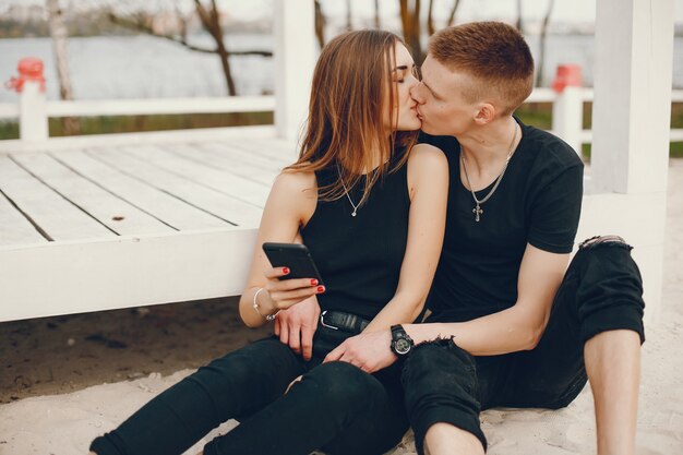 Una elegante y hermosa pareja vestida de negro pasa un buen rato en la playa