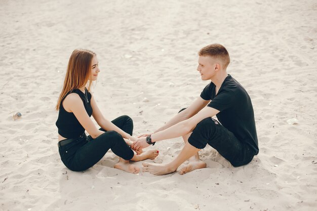 Una elegante y hermosa pareja vestida de negro pasa un buen rato en la playa