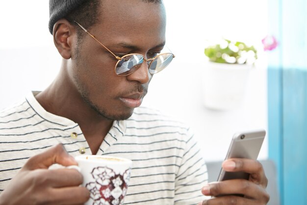 Elegante hombre afroamericano sentado en la cafetería