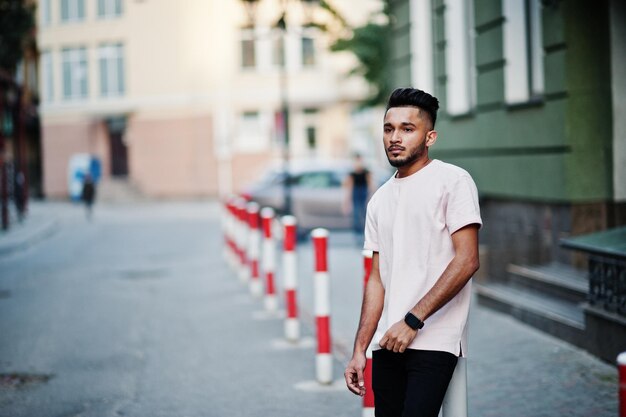 Elegante hombre de barba india con camiseta rosa Modelo de India posado al aire libre en las calles de la ciudad