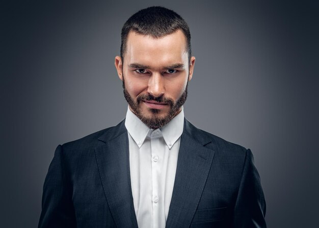 Un elegante hombre barbudo vestido con un traje de negocios y una camisa blanca.