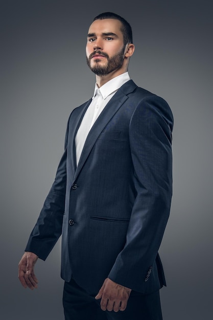 Un elegante hombre barbudo vestido con un traje de negocios y una camisa blanca.