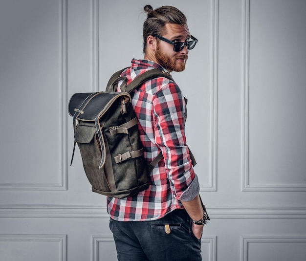 Foto gratuita elegante hombre hipster barbudo que muestra una mochila de cuero en la espalda.