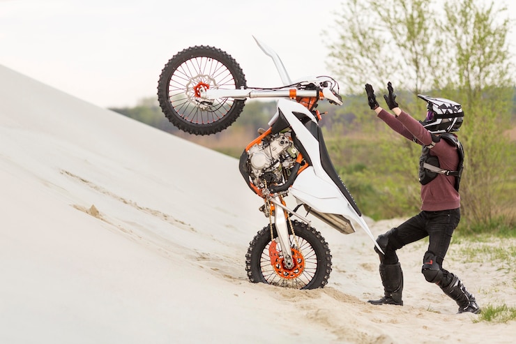 Foto gratuito elegante hombre levantando moto en el desierto