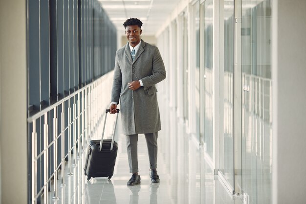 Elegante hombre negro en el aeropuerto con una maleta