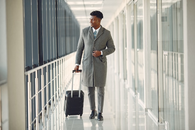 Elegante hombre negro en el aeropuerto con una maleta