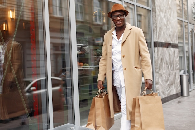 Elegante hombre negro en una ciudad con bolsas de compras