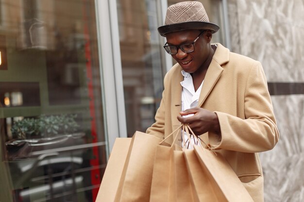 Elegante hombre negro en una ciudad con bolsas de compras