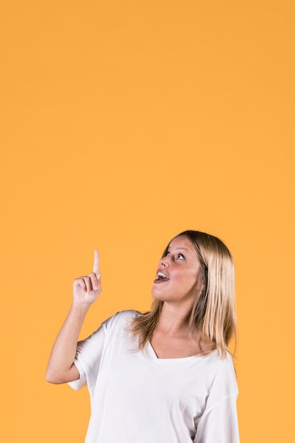 Elegante joven apuntando hacia arriba con la boca abierta