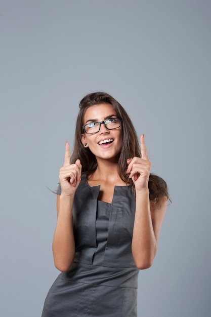 Foto gratuita elegante joven empresaria apuntando hacia arriba