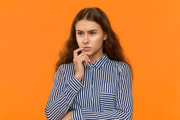 Elegante joven empresaria posando en estudio con profunda mirada pensativa de pensamientos