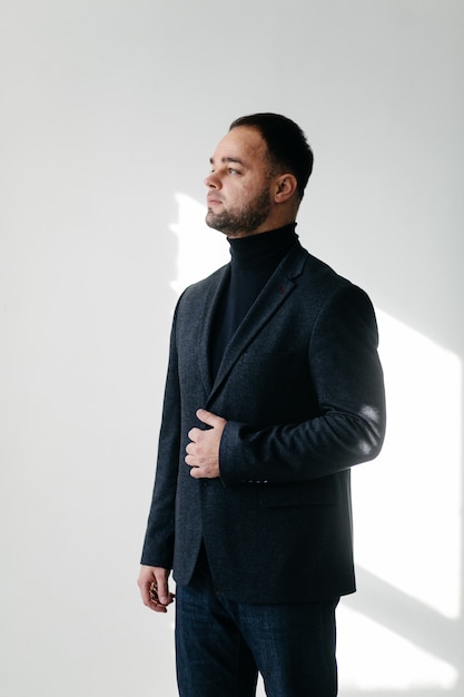 Elegante joven guapo en traje negro clásico. Retrato de estudio de moda.