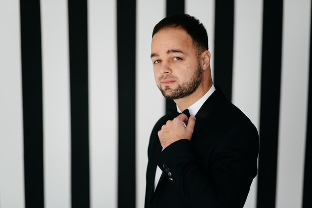 Elegante joven guapo en traje negro clásico. Retrato de estudio de moda.