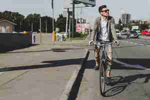 Foto gratuita elegante joven montando bicicleta en la calle