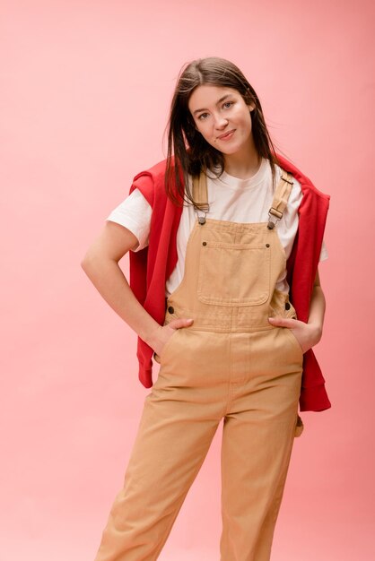 Elegante joven morena caucásica posando durante la sesión de fotos en el estudio sobre fondo rosa Estilo de vida de ocio y concepto de belleza