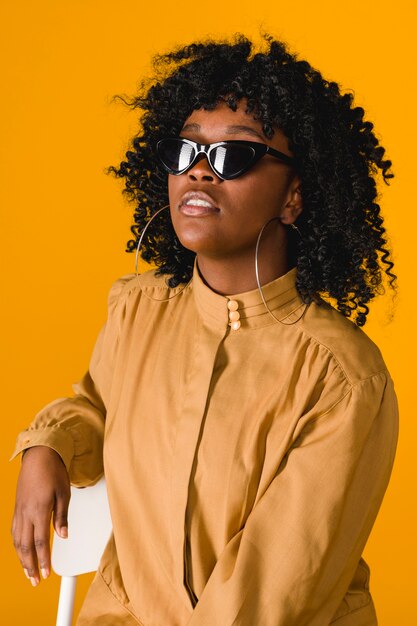 Elegante joven mujer negra con gafas de sol y aros