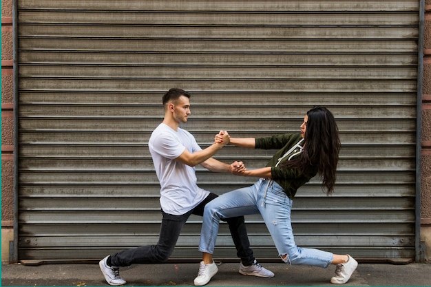 Foto gratuita elegante joven pareja bailando frente a la pared corrugada