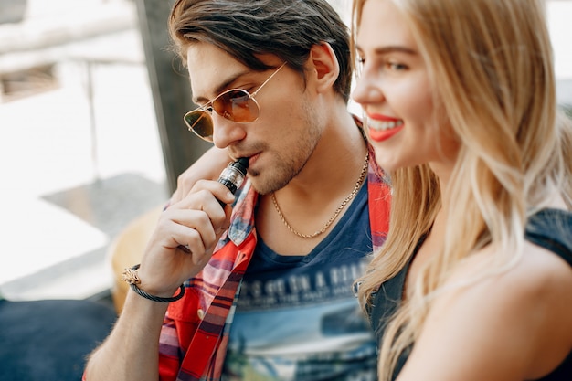 Elegante joven pareja con vape en un café