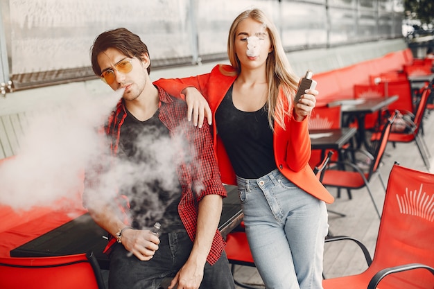 Foto gratuita elegante joven pareja con vape en una ciudad