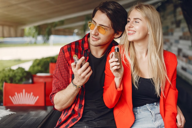 Foto gratuita elegante joven pareja con vape en una ciudad