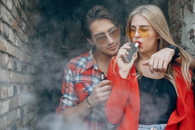 Elegante joven pareja con vape en una ciudad