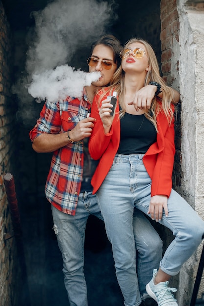 Elegante joven pareja con vape en una ciudad