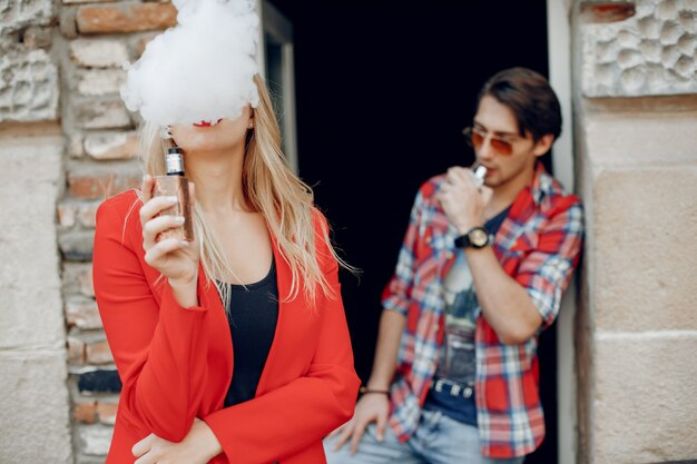 Elegante joven pareja con vape en una ciudad