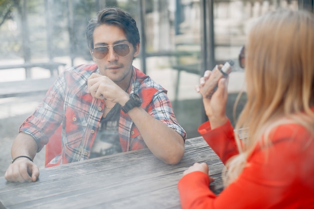 Foto gratuita elegante joven pareja con vape en una ciudad