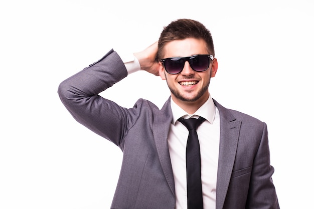Elegante y joven. Retrato de hombre joven guapo con gafas de sol y ropa formal mirando a la cámara mientras está de pie contra el fondo gris