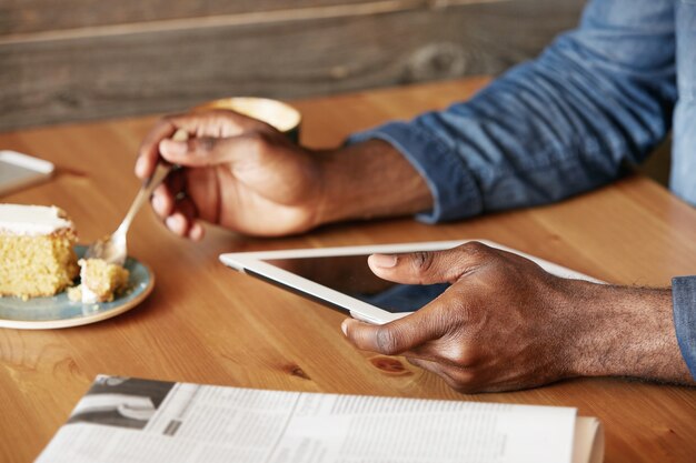 Elegante joven sentado en la cafetería con tableta