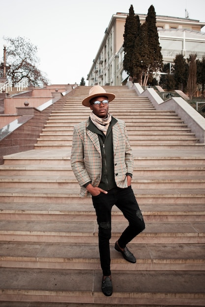 Elegante macho adulto posando al aire libre con sombrero moderno