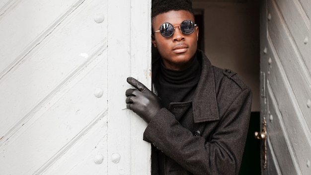 Foto gratuita elegante macho adulto posando con gafas de sol y guantes