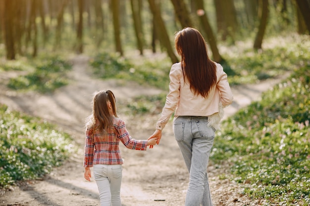 Elegante madre con hija en un bosque de verano