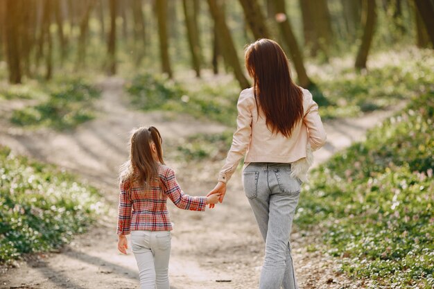 Elegante madre con hija en un bosque de verano