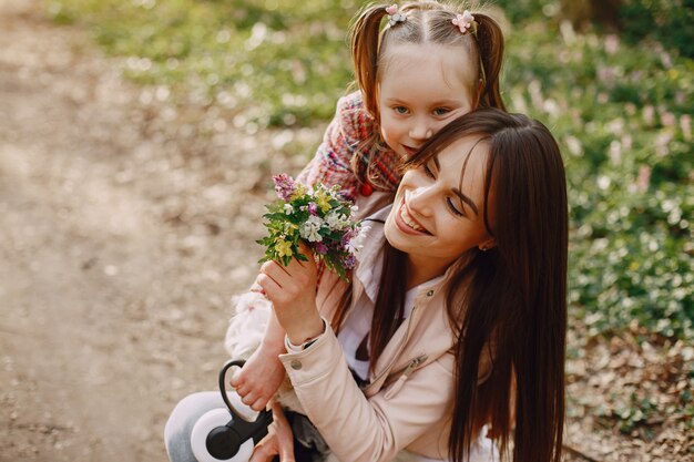 Elegante madre con hija en un bosque de verano