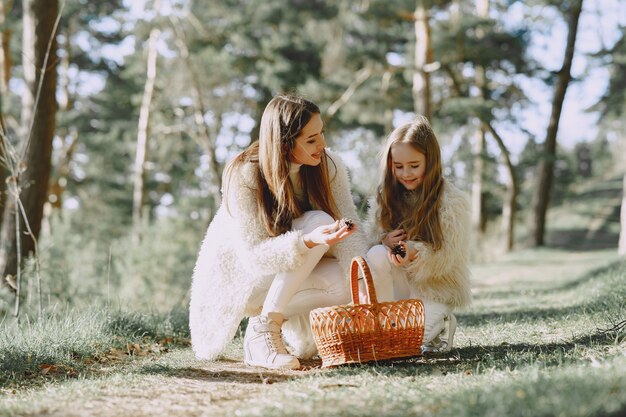 Elegante madre con hija en un bosque de verano