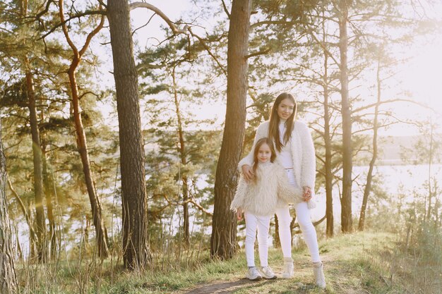 Elegante madre con hija en un bosque de verano