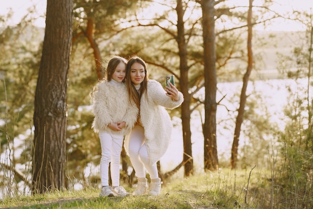 Elegante madre con hija en un bosque de verano