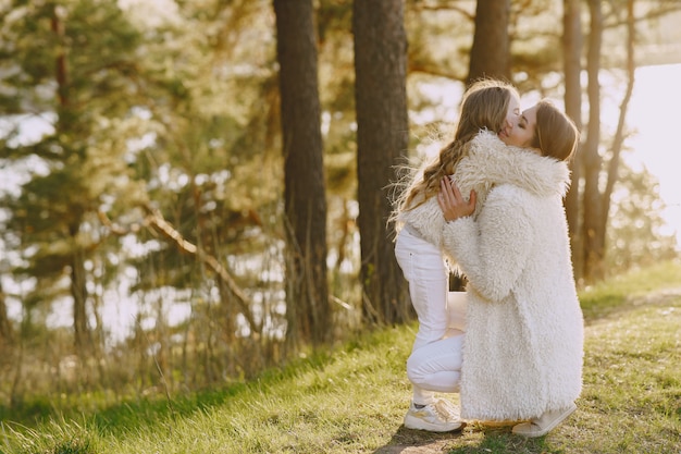 Elegante madre con hija en un bosque de verano