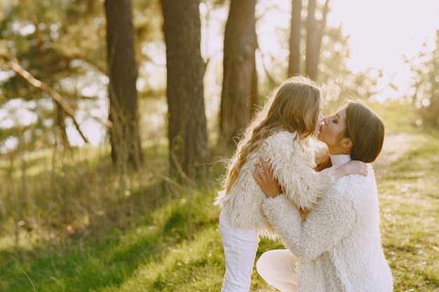 Elegante madre con hija en un bosque de verano