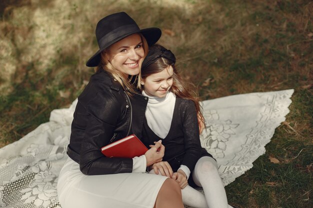 Elegante madre con hija en un bosque de verano